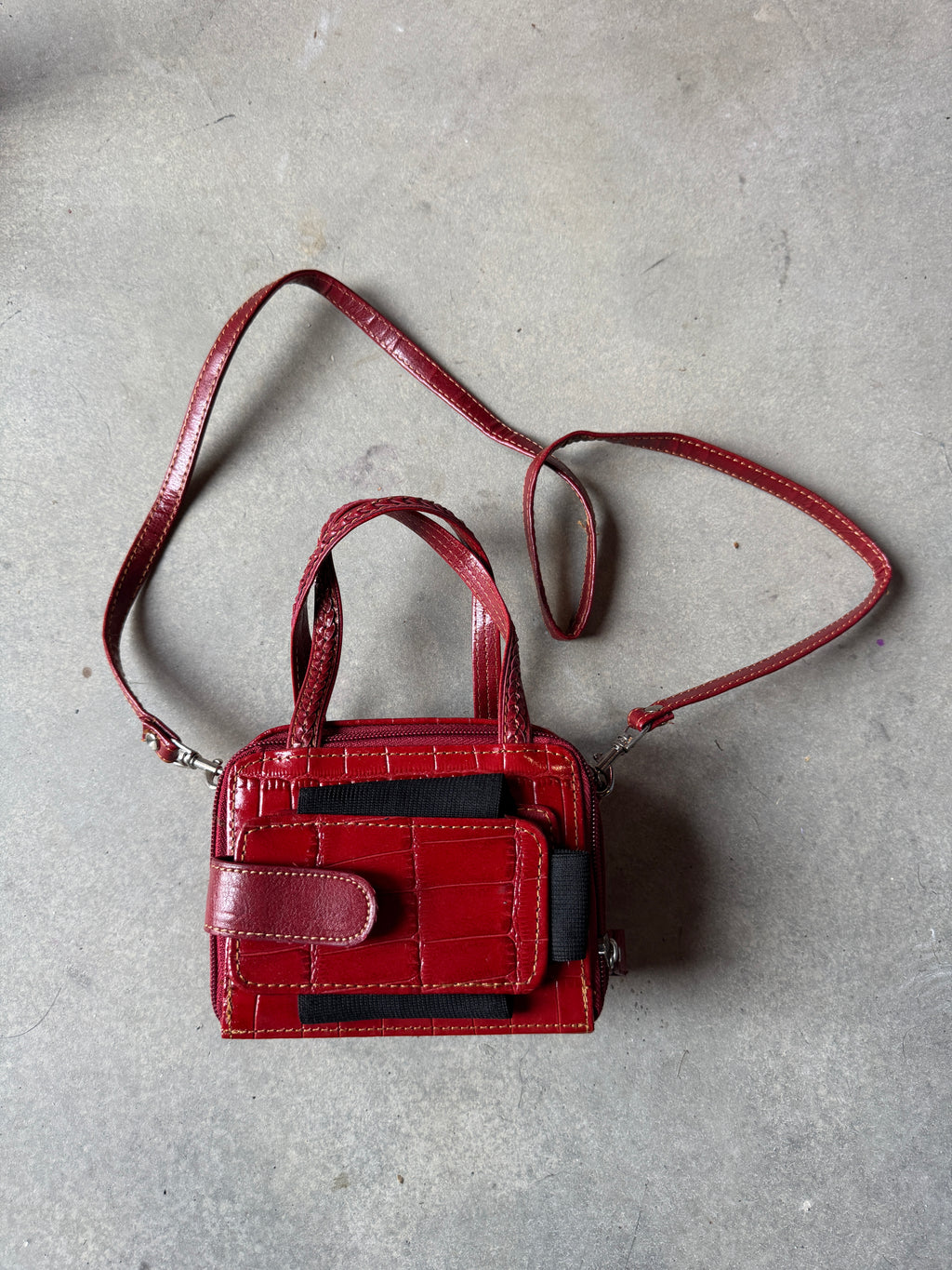 Red handbag with a strap on a gray concrete surface