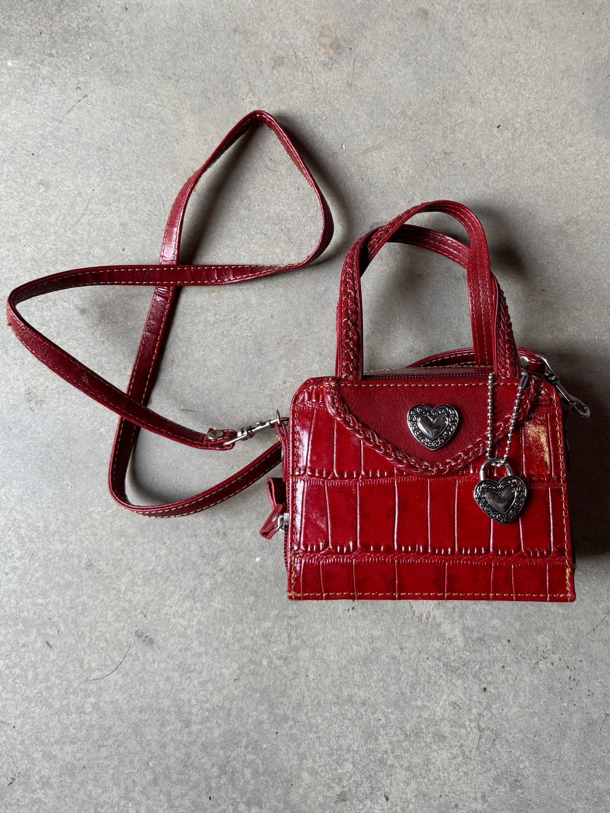 Red handbag with a strap on a gray concrete surface