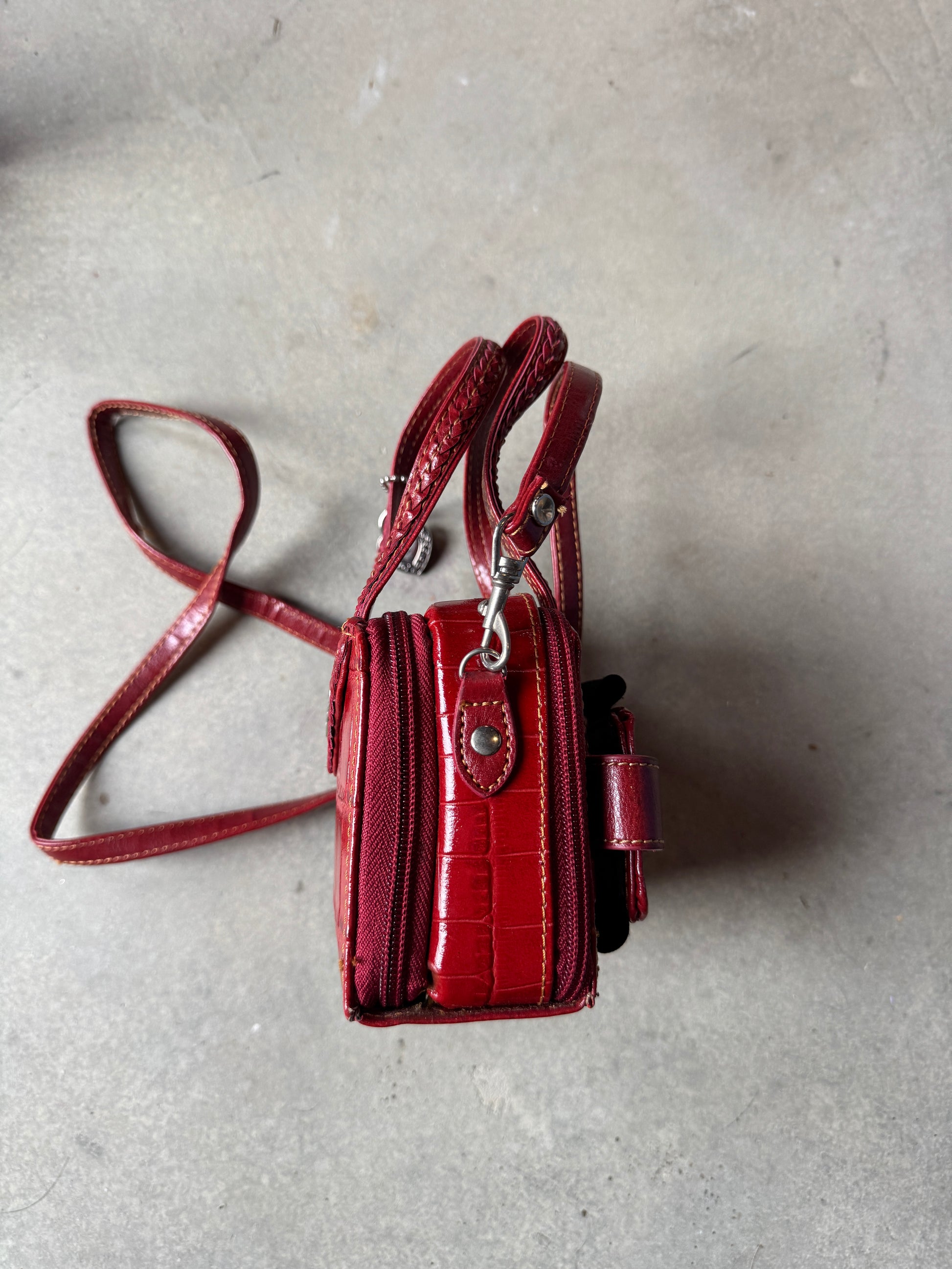 Red handbag with a strap on a gray surface