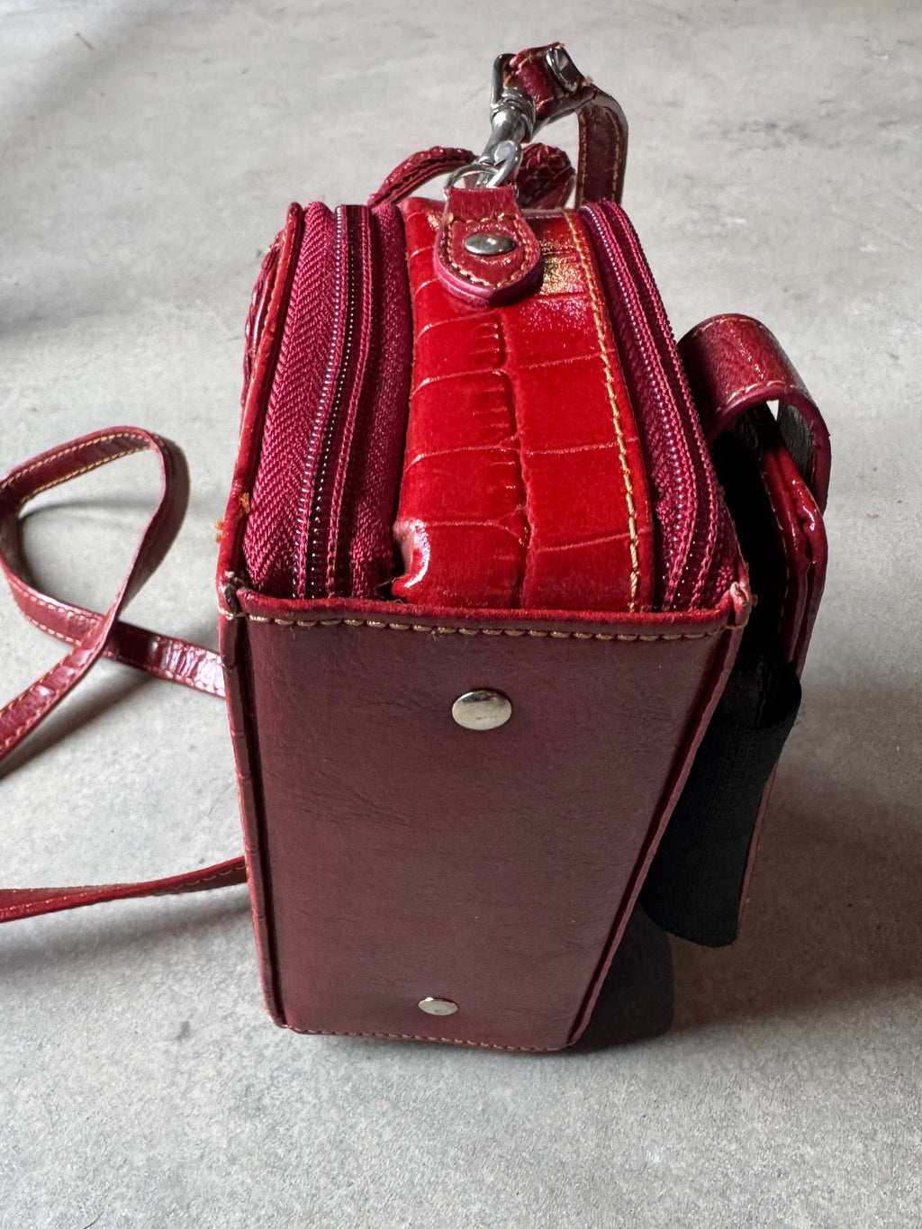 Red handbag with a strap on a light gray surface